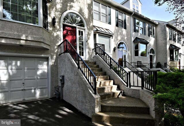 entrance to property featuring a garage and stucco siding