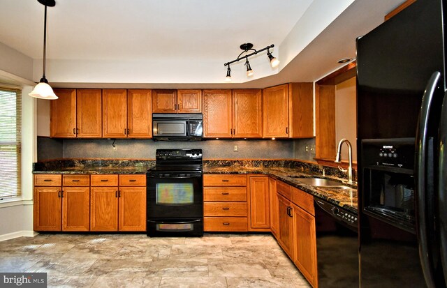 kitchen with pendant lighting, dark stone counters, brown cabinets, a sink, and black appliances