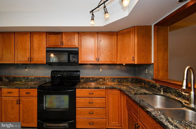 kitchen with brown cabinetry, a sink, dark stone countertops, backsplash, and black appliances