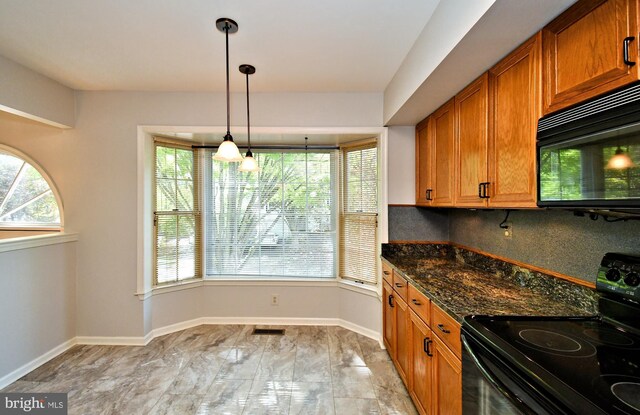 kitchen featuring dark stone countertops, brown cabinetry, black appliances, and tasteful backsplash