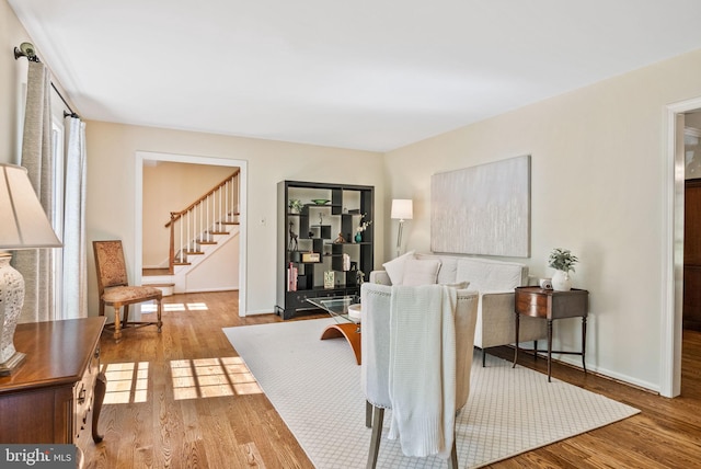 living room with stairway, baseboards, and wood finished floors