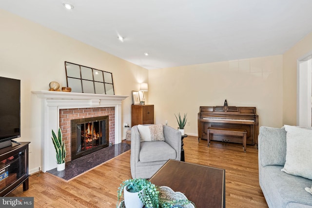 living room featuring a fireplace, recessed lighting, and wood finished floors