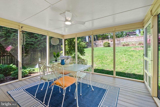 sunroom / solarium with a ceiling fan and outdoor dining space