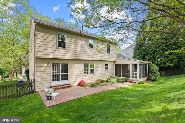 rear view of property featuring fence, a yard, a sunroom, and a patio area