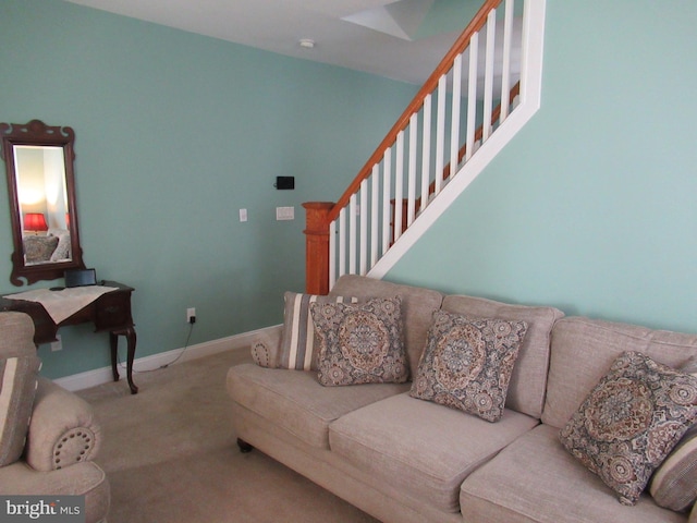 carpeted living area with baseboards and stairs
