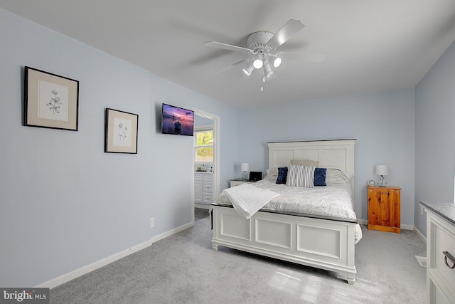 bedroom with light colored carpet, a ceiling fan, ensuite bath, and baseboards