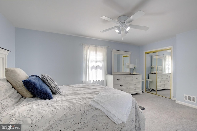bedroom with visible vents, ceiling fan, a closet, baseboards, and light carpet