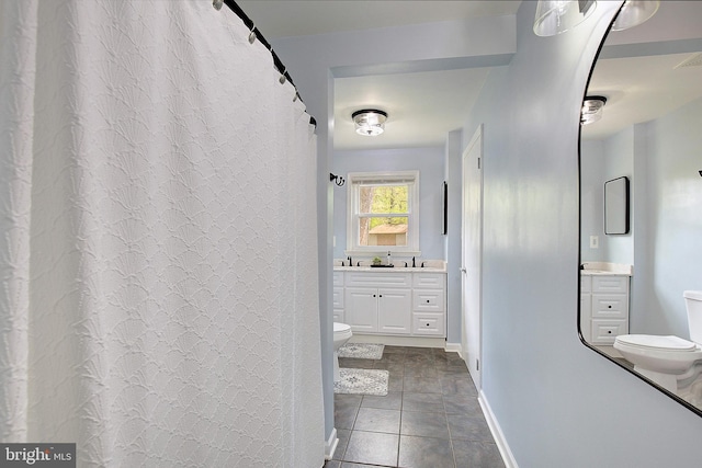bathroom featuring toilet, tile patterned floors, vanity, and baseboards