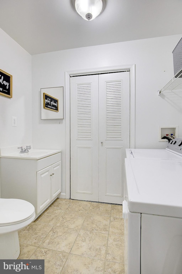 bathroom with toilet, vanity, separate washer and dryer, and a closet
