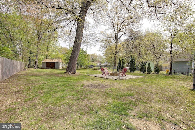 view of yard featuring fence, a fire pit, and an outdoor structure