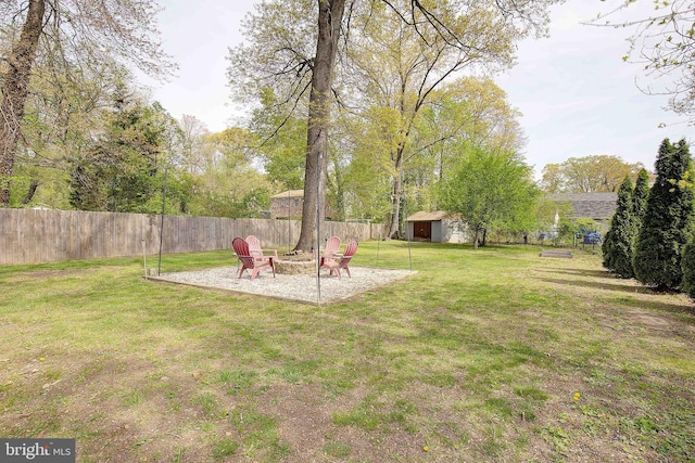 view of yard with a fire pit, a patio, a storage unit, an outbuilding, and a fenced backyard