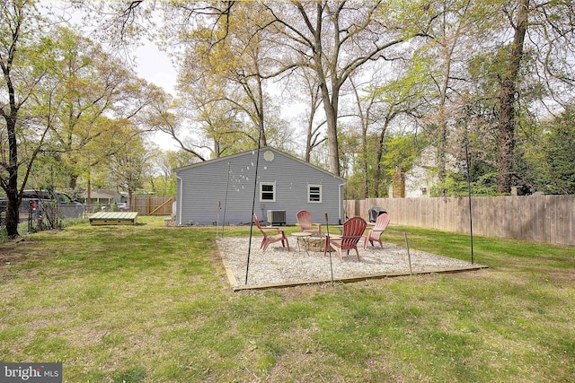 exterior space with an outdoor fire pit, a fenced backyard, cooling unit, and a lawn