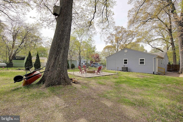 view of yard with a fire pit, a fenced backyard, a patio area, and central air condition unit