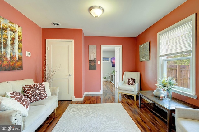 living area with wood finished floors, visible vents, and baseboards
