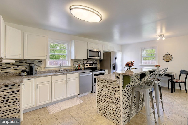 kitchen with a wealth of natural light, backsplash, appliances with stainless steel finishes, and a sink