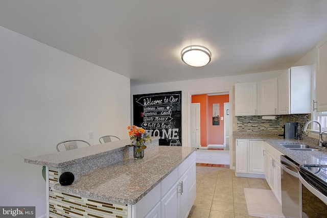 kitchen featuring dishwasher, a sink, white cabinets, and tasteful backsplash