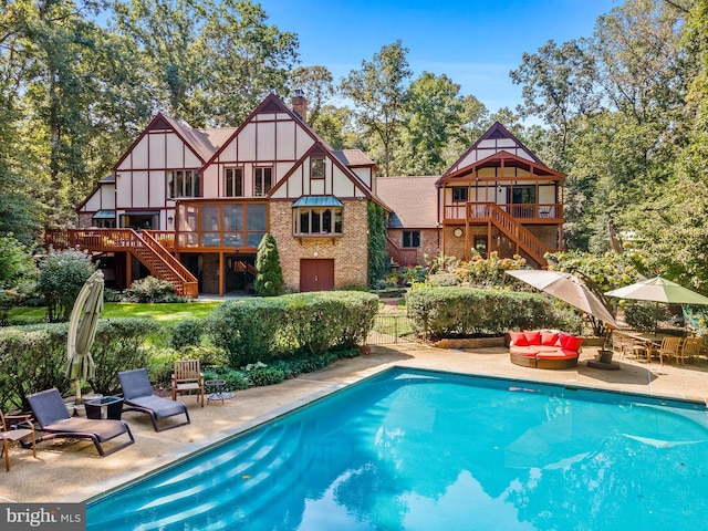 pool with a patio, a wooden deck, and stairs