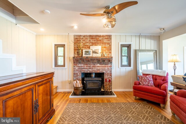 3734 1st Ave, Edgewater, MD 21037 - living room with crown molding, a wood stove, light wood-style floors, baseboards, and a ceiling fan