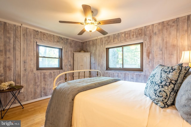 3734 1st Ave, Edgewater, MD 21037 - bedroom featuring baseboards, wood walls, multiple windows, and light wood finished floors