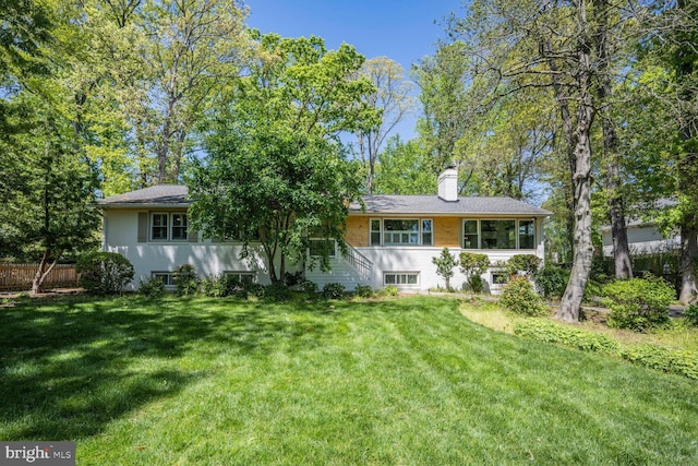 rear view of house featuring a lawn, fence, and a chimney