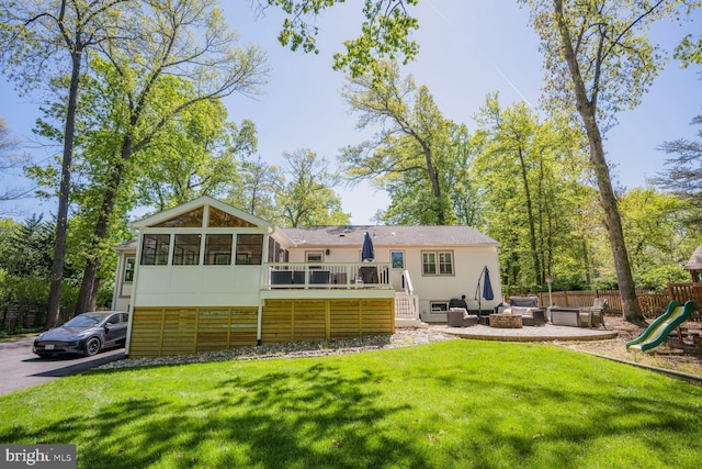 back of house featuring a wooden deck, a sunroom, fence, a playground, and a yard