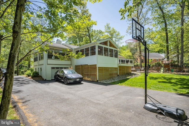 view of vehicle parking featuring fence, an attached garage, a playground, and driveway