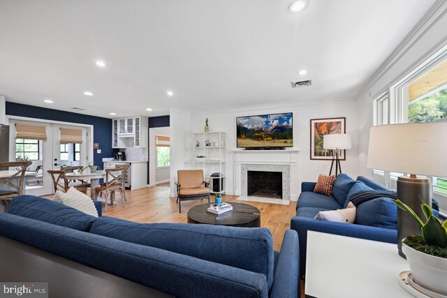 living area with light wood-style floors, recessed lighting, a fireplace with flush hearth, and visible vents