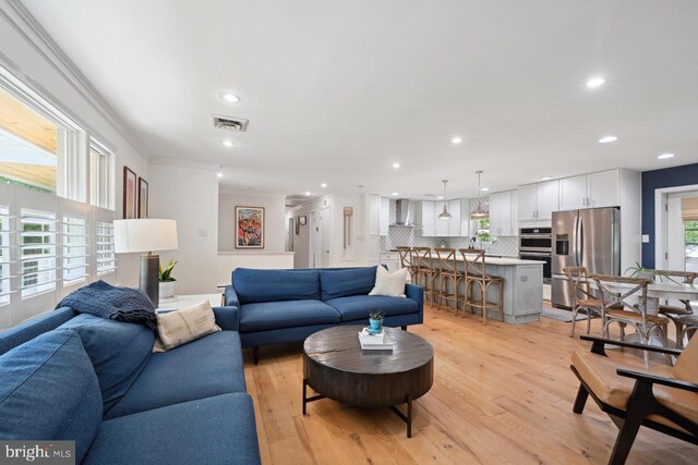 living room with recessed lighting, ornamental molding, light wood-type flooring, and visible vents