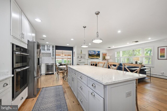 kitchen featuring wine cooler, a kitchen breakfast bar, a center island, backsplash, and stainless steel appliances