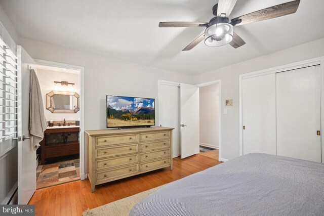 bedroom with light wood-style floors, a ceiling fan, a sink, and ensuite bathroom