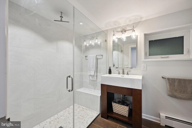 bathroom featuring a baseboard heating unit, a shower stall, and vanity