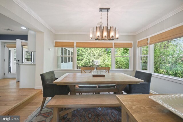 dining area with a chandelier, baseboards, wood finished floors, visible vents, and ornamental molding
