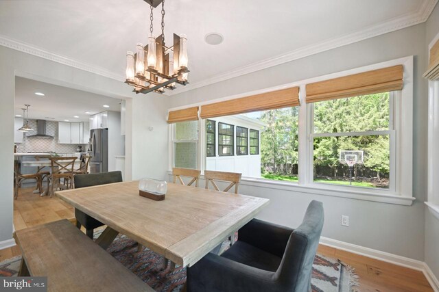 dining area featuring baseboards, ornamental molding, a healthy amount of sunlight, and light wood-type flooring