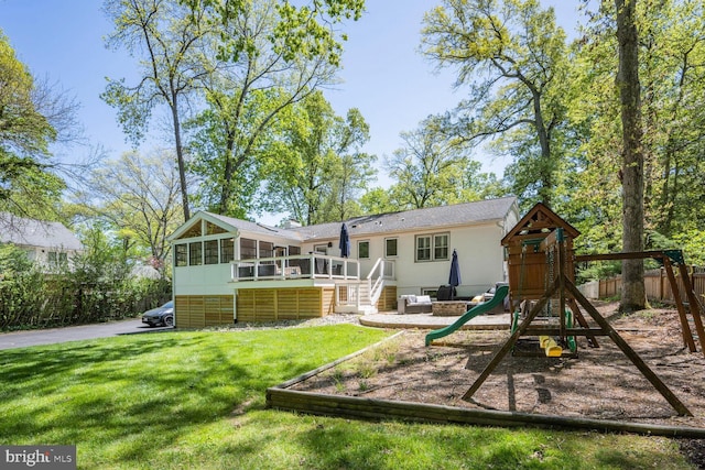 rear view of property with a sunroom, fence, a playground, a yard, and stairs