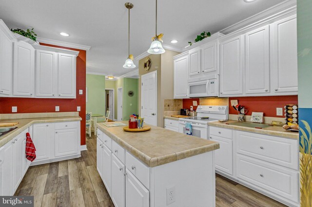 33 Douglas St, Reedville, VA 22539 - kitchen featuring light wood-type flooring, crown molding, white cabinetry, a kitchen island, and white appliances