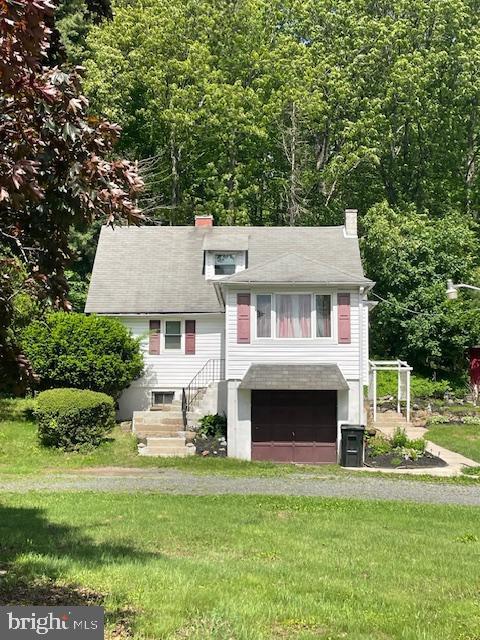 view of front of property with a garage, a chimney, driveway, and a front lawn