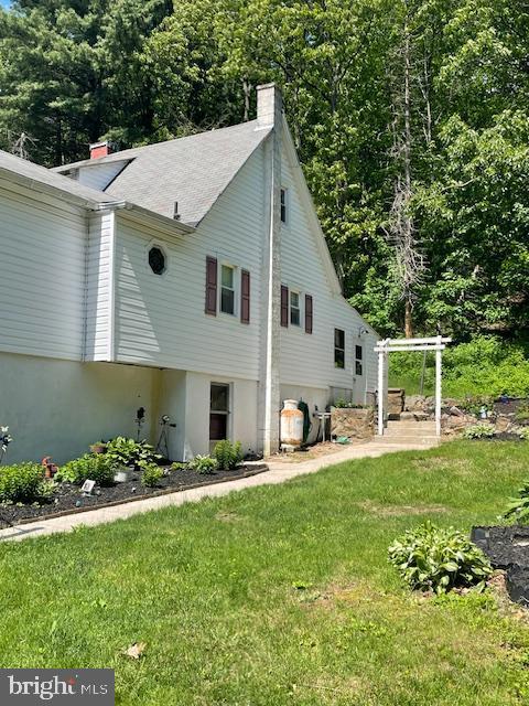 view of property exterior with a chimney and a yard