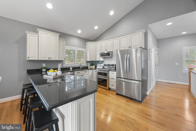 kitchen featuring a sink, stainless steel appliances, a breakfast bar area, a peninsula, and white cabinetry
