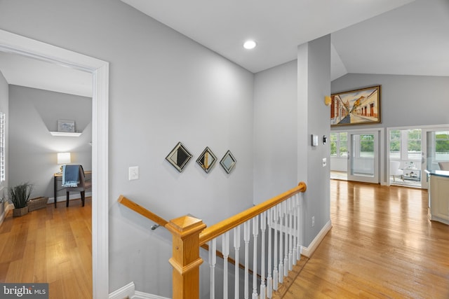 corridor featuring an upstairs landing, light wood finished floors, and baseboards