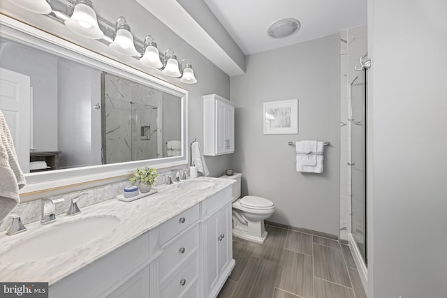 full bath featuring toilet, a stall shower, double vanity, and a sink