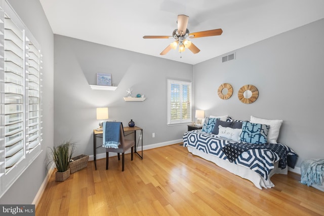 bedroom with a ceiling fan, visible vents, wood finished floors, and baseboards