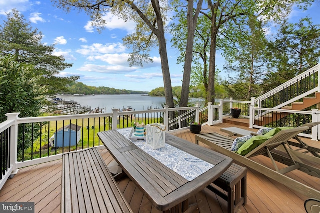 wooden deck with stairway, a water view, and outdoor dining area