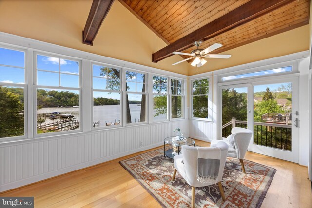 sunroom / solarium with lofted ceiling with beams, wooden ceiling, a deck with water view, and wood finished floors