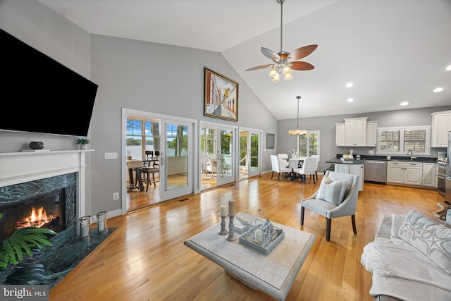 living area featuring recessed lighting, high vaulted ceiling, ceiling fan, light wood-type flooring, and a high end fireplace