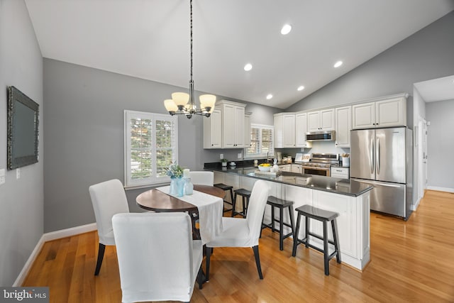 dining area with recessed lighting, a notable chandelier, light wood-style flooring, baseboards, and lofted ceiling