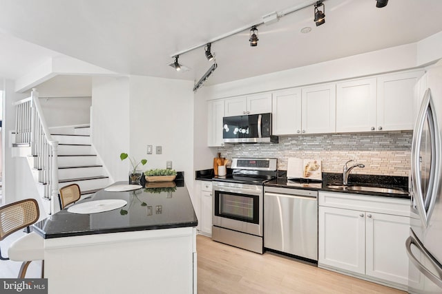 1301 N Courthouse Rd Unit 1812, Arlington, VA 22201 - kitchen featuring appliances with stainless steel finishes, tasteful backsplash, white cabinets, dark countertops, and light wood finished floors