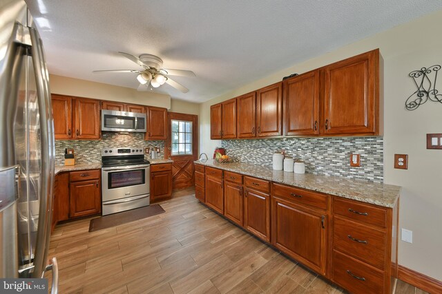 3703 Spruce St, Bristol, PA 19007 - kitchen with ceiling fan, appliances with stainless steel finishes, tasteful backsplash, brown cabinets, and light wood-style floors