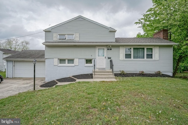 tri-level home with concrete driveway, a garage, a front lawn, and a chimney