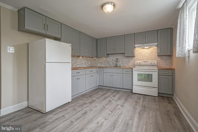 kitchen with white appliances, gray cabinetry, light wood-style flooring, and tasteful backsplash