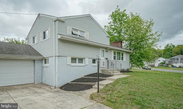 tri-level home with a front yard, concrete driveway, a chimney, and an attached garage